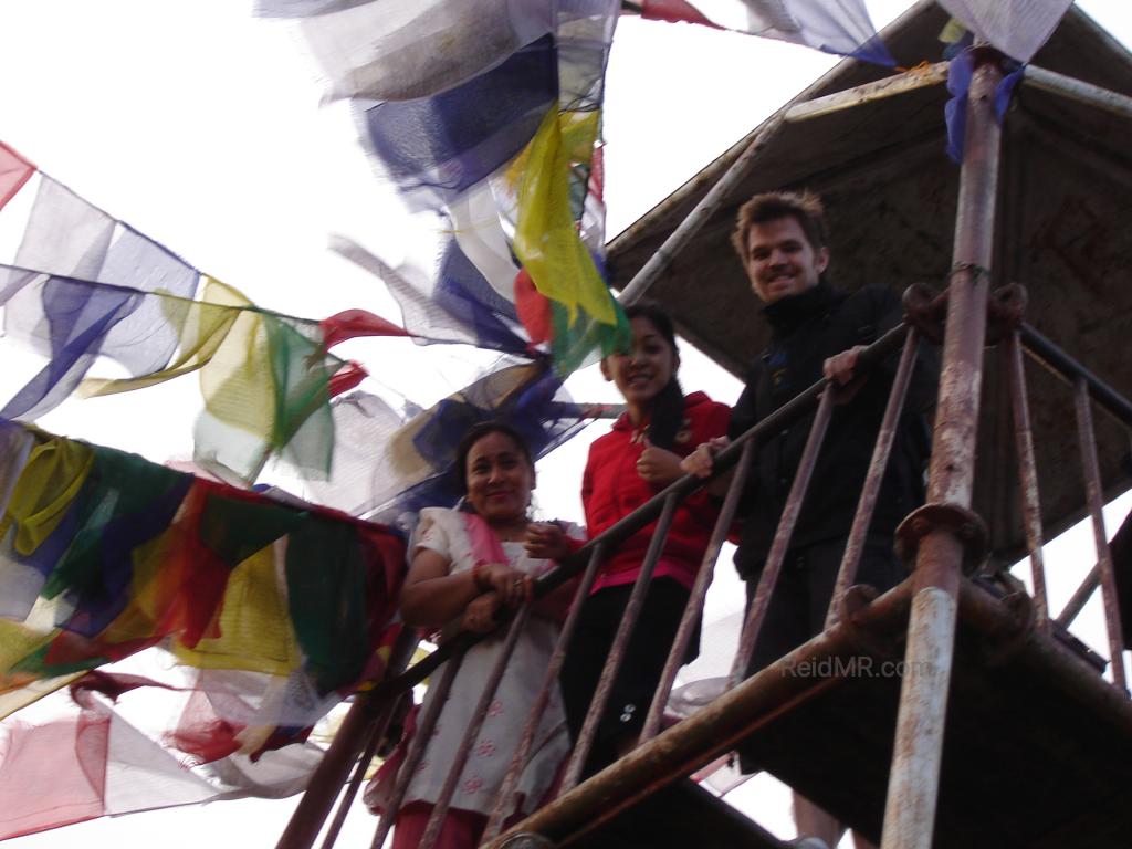 Urika, Mamu and I peering down from a tower with prayer flags waving