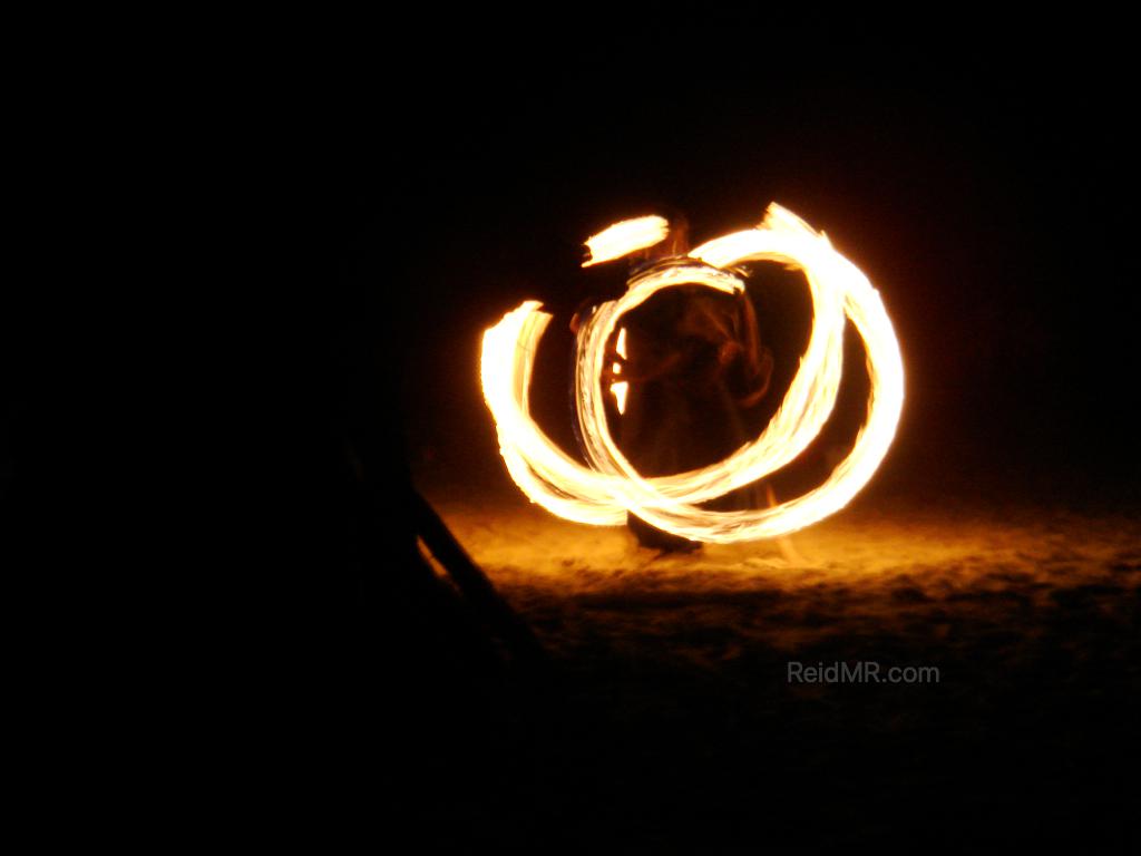 Fire dancer at night, with the light trail frozen by the camera