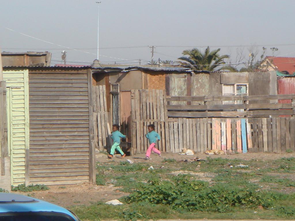 Young kids running through the township. Image of happiness in poverty.