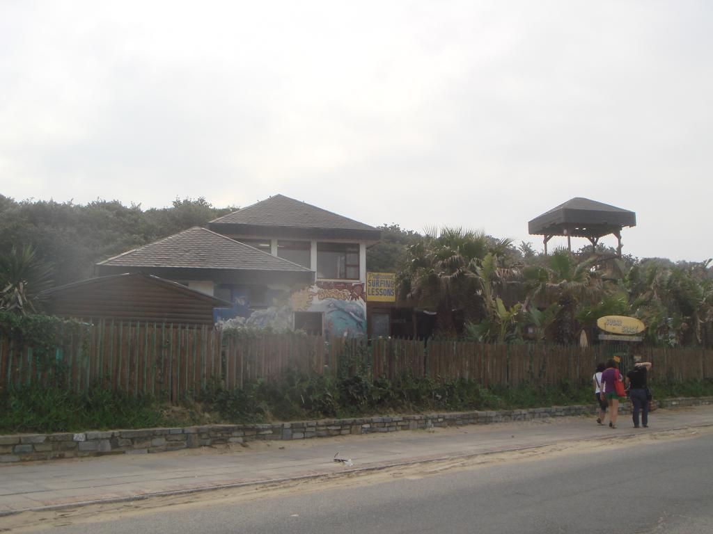 A photo of the Sugar Shack, the road in the foreground, and the shack with the hill and wilderness behind it.