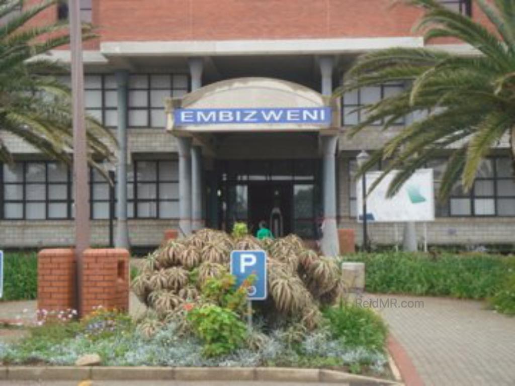 A photo of the entrance of one of the campus buildings, with the trees and flowers.