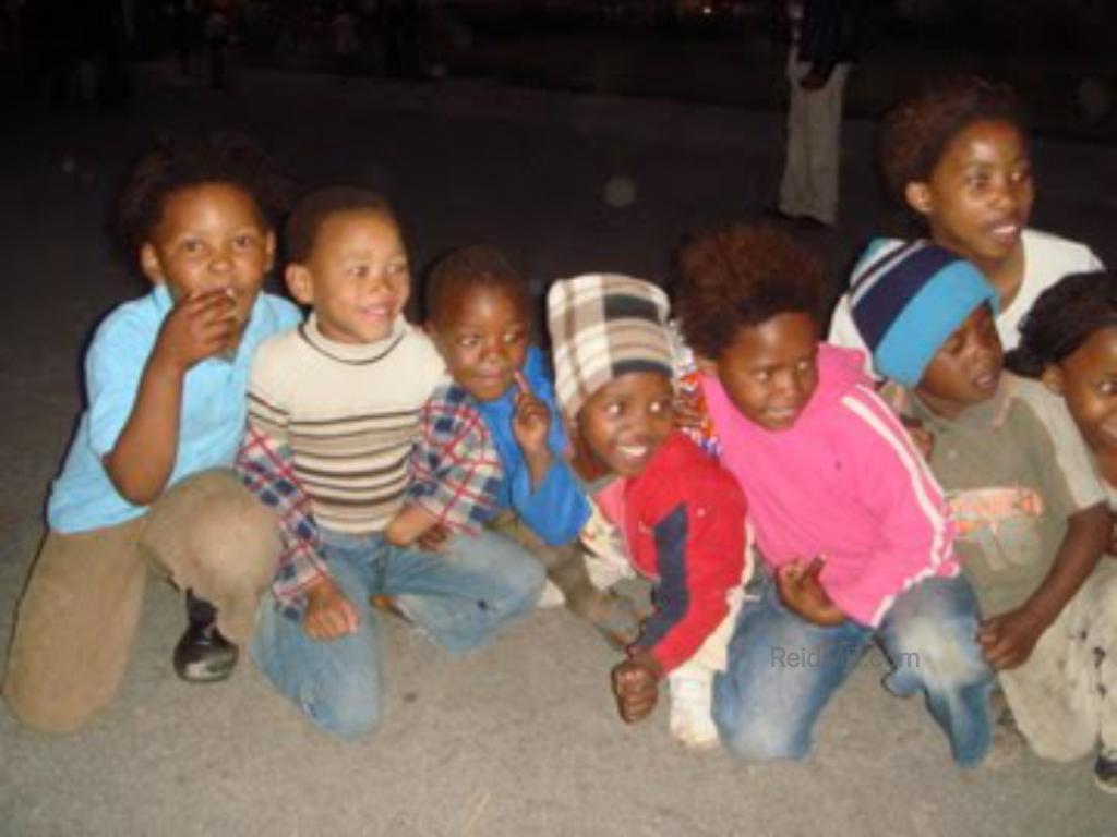 A group of local kids squatting and posing for a photo when we were on the township tour.