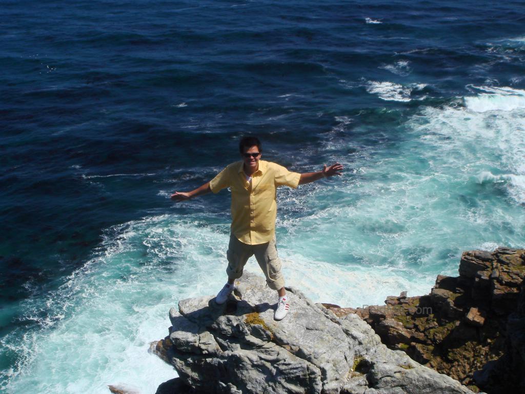 Standing on the edge of a rock jutting over the ocean.