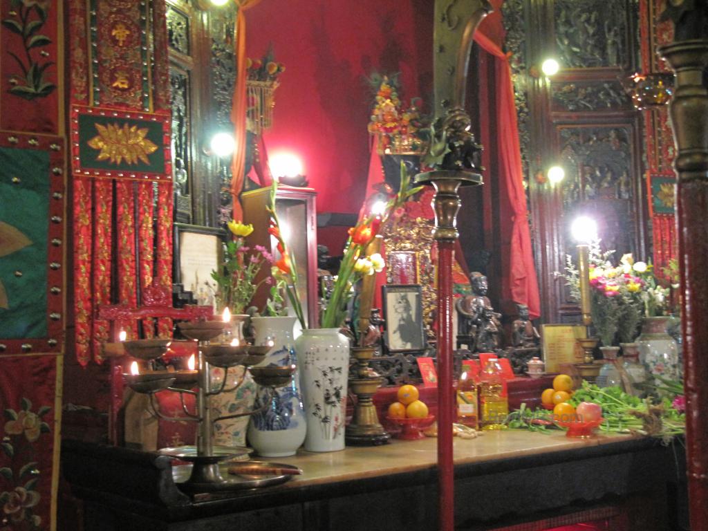 A temple in Hong Kong, the main worship area with the Buddha, fruit, incense and candles. 