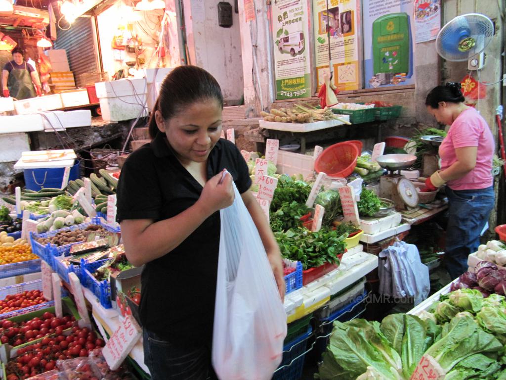 Likee in the street market putting something in a bag. 