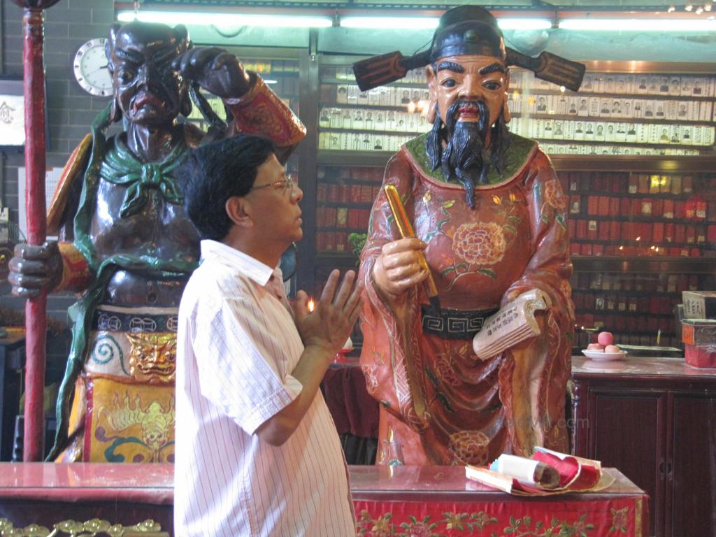 Dad praying at the temple, with a statute of a god behind him. 