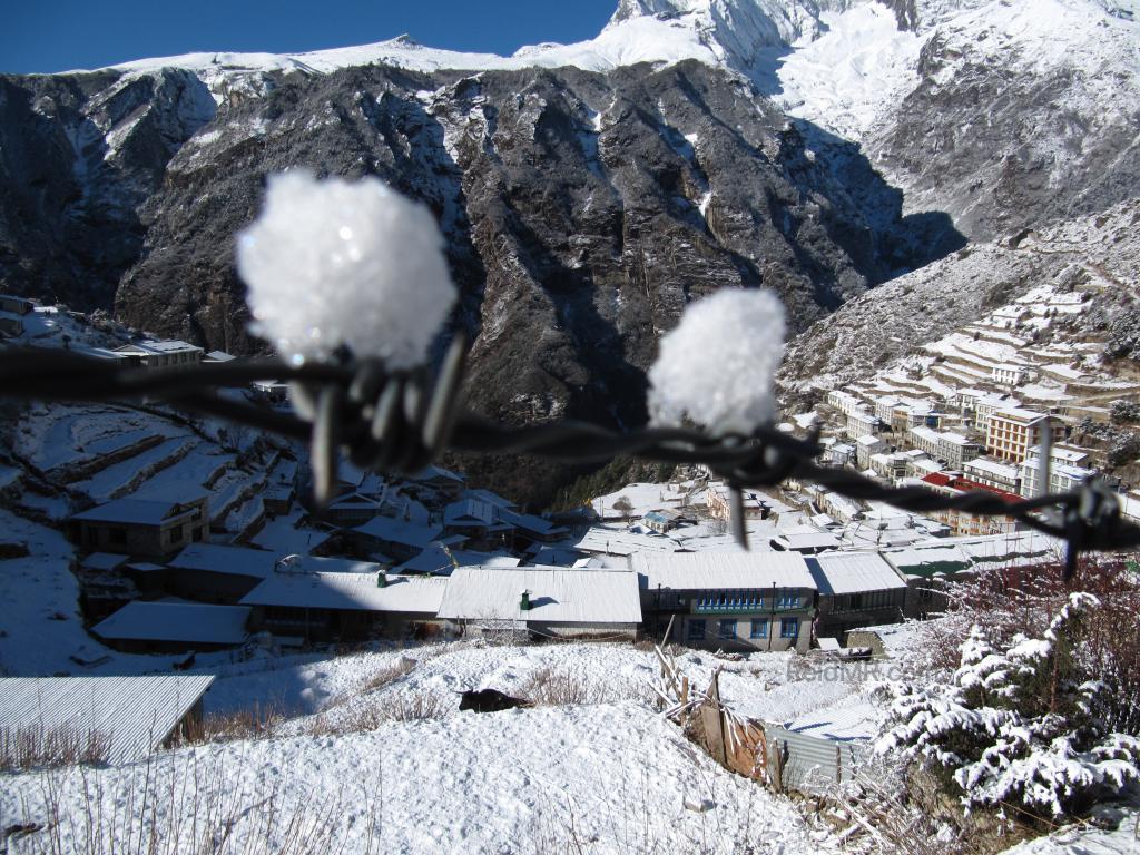 Snow on a barbed wire fence, with Namche Bazar in the background