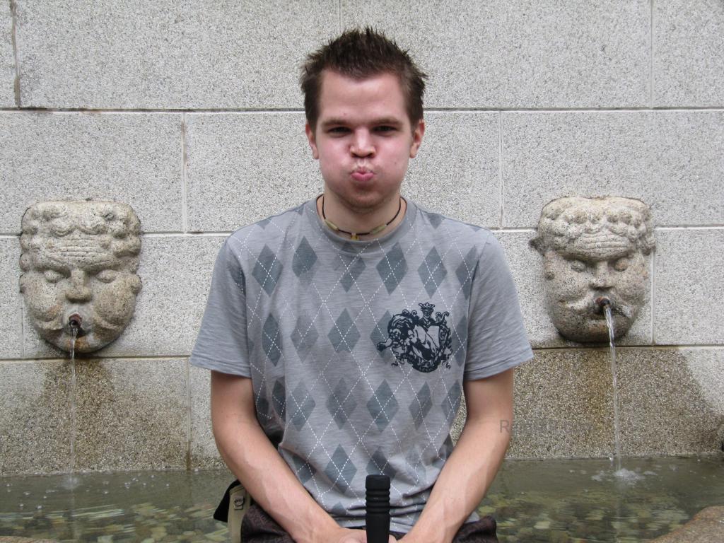 Me with some sculpted faces spouting water out of the mouth, I am making a weird face. 