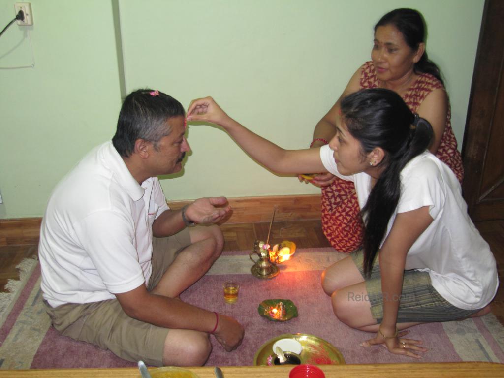 Urika is giving dad her blessing and putting a tika on his forehead