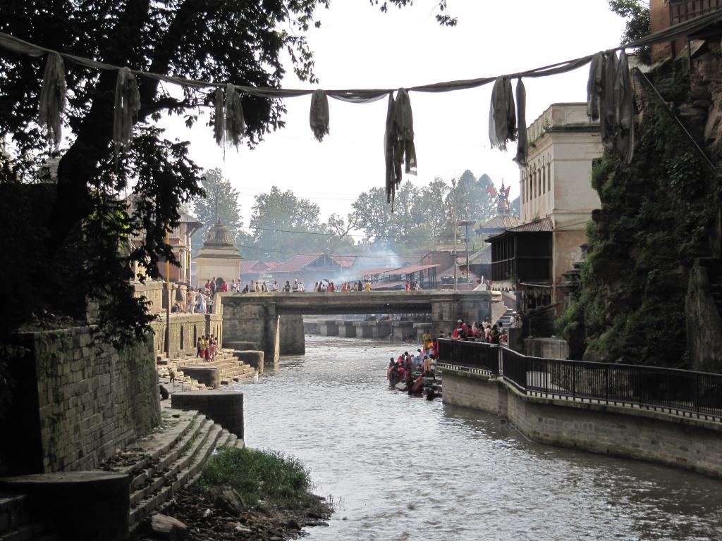 The Pashupatinath Temple, with the river running next to it. Can see people and fires burning. 