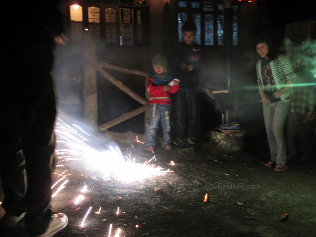 Kids lighting fireworks outside, with one burning