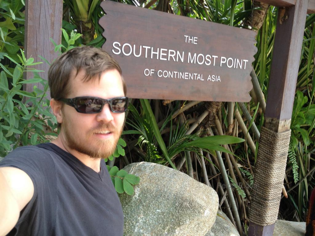 Me standing with a sign proclaiming the southernmost part of continental Asia