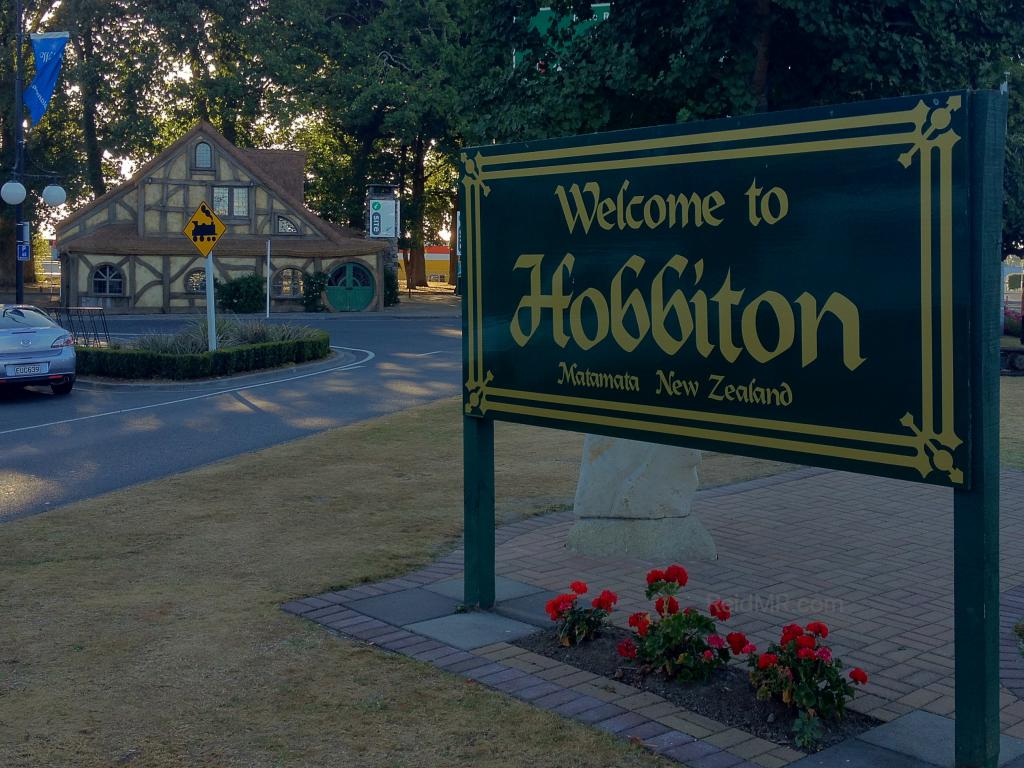 Sign for Matamata AKA Hobbiton with the themed town info center in the background.